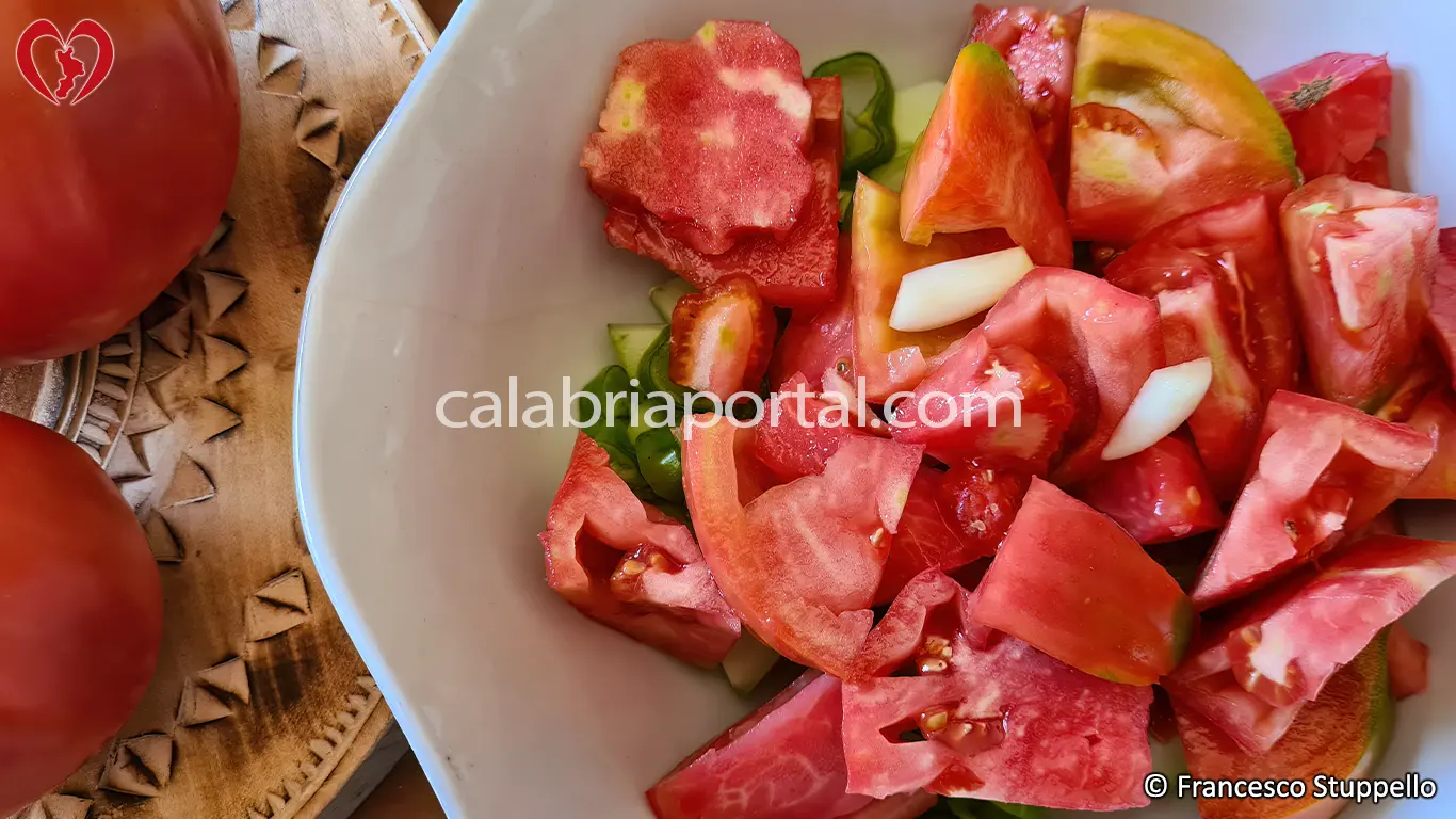 Ricetta dell'Insalata di Pomodori, Cetrioli e Peperoni alla Calabrese: tagliate a pezzi i pomodori.