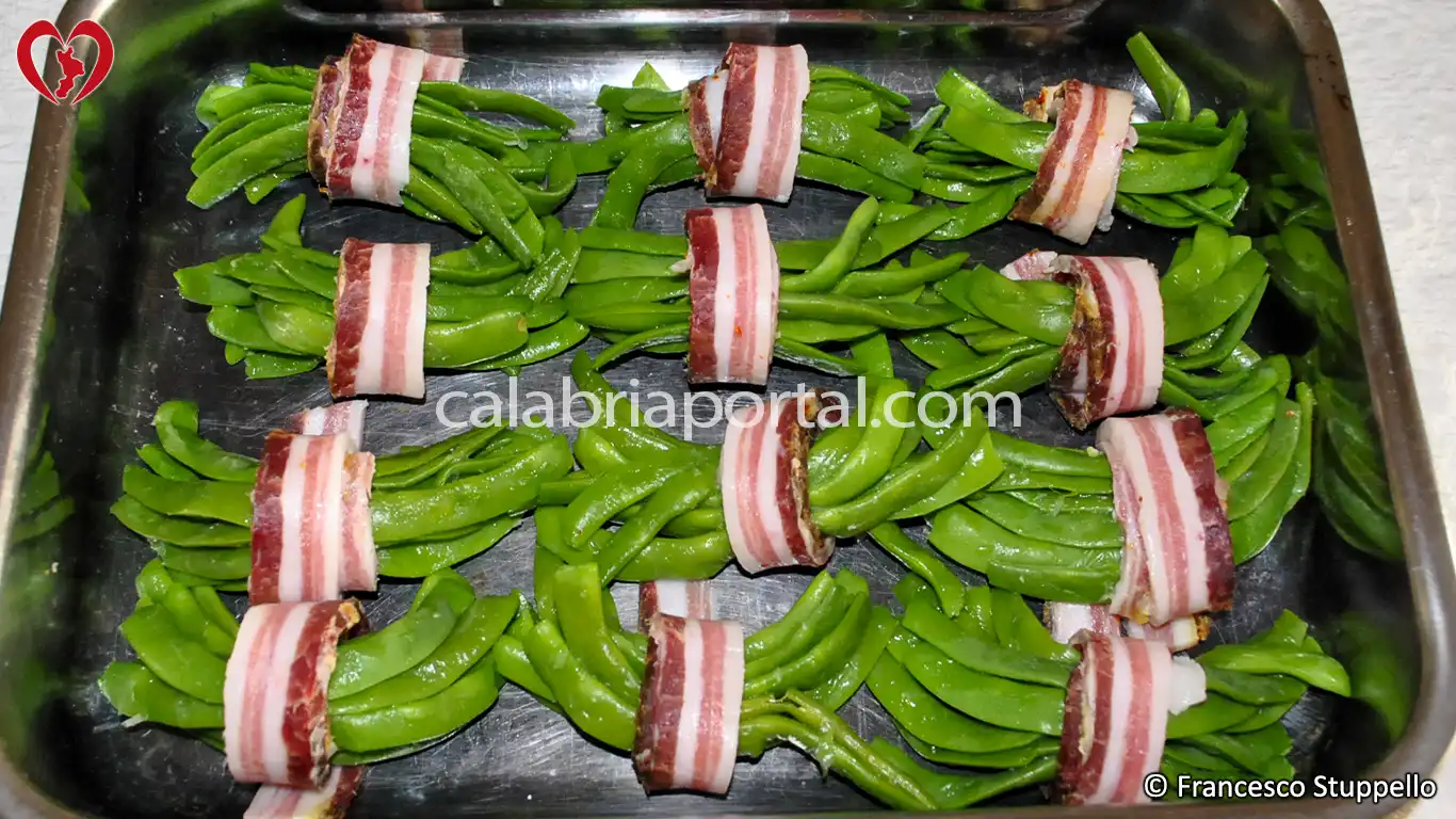 Ricetta degli Involtini di Fagiolini e Pancetta: ponte gli involtini nella teglia Ricetta degli Involtini di Fagiolini e Pancetta: ponte gli involtini nella teglia